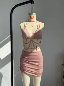 Dettaglio del set bikini rosa con catene in metallo dorato e gonna con lacci laterali