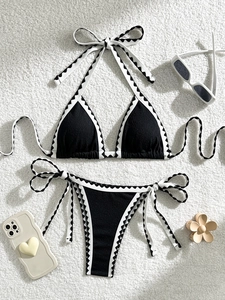Close-up of black scalloped bikini with white trim and summer vacation accessories