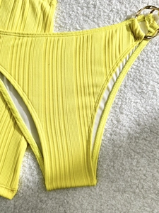 Bright yellow ribbed bikini bottom with gold rings and textured fabric for beach vacation