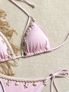 Detail of pink ribbed bikini featuring shell pendants and white crochet lace edges