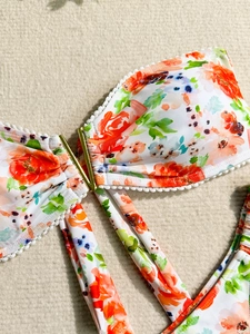 Haut de bikini floral avec boucle en V dorée et finitions délicates en dentelle blanche