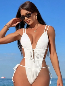 White ribbed one-piece swimsuit with deep V-neck and cut-out waist detail at the beach