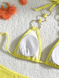 Detailed macro view of yellow ribbed bikini cup with golden metal rings and fabric texture