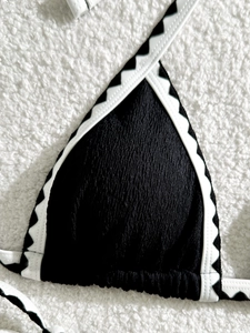 Detailed macro view of black ribbed bikini top with white wave pattern contrast piping