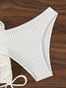 Detail of white waffle knit bikini bottom with side tie on wooden background