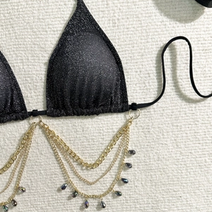 Dettaglio del top bikini in tessuto glitterato nero con catenelle dorate a più livelli