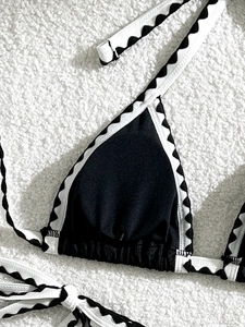 Close-up of black bikini top with white contrast piping and scalloped wave edge detail