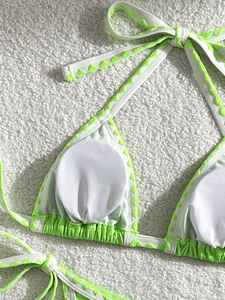Detail of white bikini top showing neon green wavy edges and removable breast pads