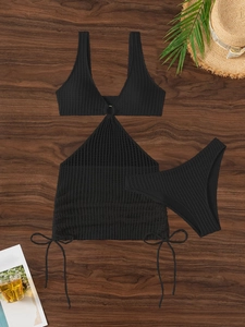 Detailed flat lay of black three-piece bikini set with knit texture on wood background