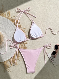 Flat lay of pink ribbed bikini with halter top and side-tie bottoms on a woven mat