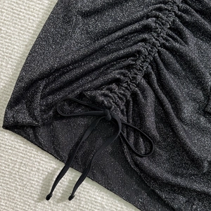 Dettaglio macro del bikini nero glitterato con coulisse arricciata e tessuto luccicante