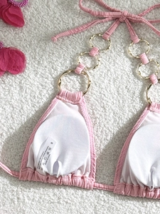 Detail of pink ribbed bikini top with golden ring connectors and white chest pads