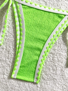 Detail of neon green textured bikini bottom with white trim and green triangle embroidery