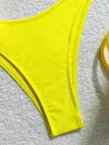 Detail of neon yellow bikini bottom with reinforced zigzag stitching on elastic fabric