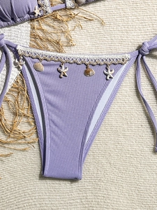 Macro detail of lavender ribbed bikini bottoms with seashell and starfish charms on lace