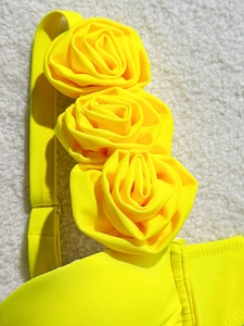 Macro view of handmade 3D floral roses on vibrant yellow push-up bikini shoulder straps