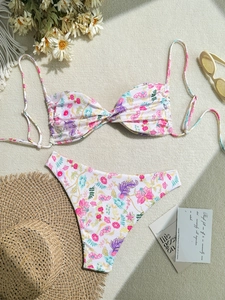 Detailed flat lay of a floral bikini set with high-waisted bottoms on a woven beach mat