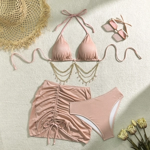 Dettaglio bikini a 3 pezzi glitter rosa con catenelle dorate e accessori per la spiaggia