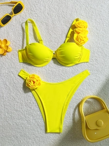 Detailed flat lay of bright yellow underwire bikini with 3D rose flower accents on white rug