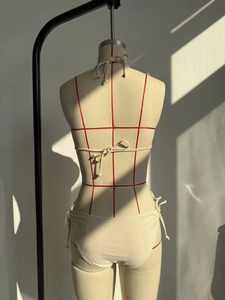 Vista posterior de bikini halter color crema con lazos de cierre sobre maniquí de costura