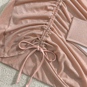 Vista macro del tessuto arricciato metallizzato oro rosa con dettaglio coulisse bikini