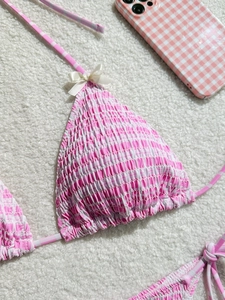 Haut de bikini smocké à carreaux roses et blancs avec petit nœud blanc sur fond doux