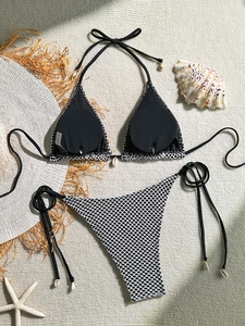 Detail view of black mesh bikini set with seashell decor and S-size label on sand mat
