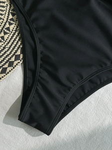 Chic black halter one-piece swimsuit with high-cut leg and premium ribbed texture