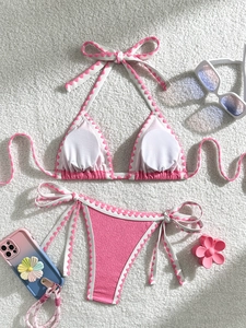 Pink bikini set with textured fabric and white trim detail on soft white plush backdrop