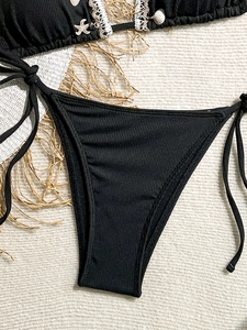 Detail of black ribbed bikini with crochet lace trim and seashell starfish charms