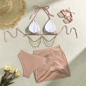 Dettaglio del top bikini con elegante catena dorata e ciondoli di cristallo su sfondo chiaro