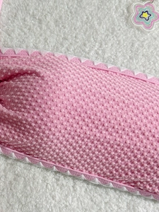 Pink bikini top with textured shell pattern and white scalloped edges in detail