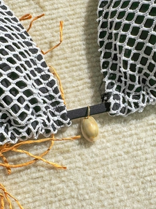 Detail of green mesh bikini featuring seashell pendant and orange raffia tassel trim