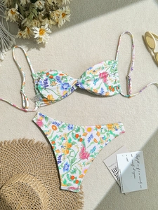 Women's two-piece floral bikini set with adjustable straps on a woven beach mat background