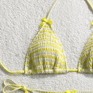 Détail du haut de bikini à rayures jaunes et blanches avec smocks et nœud décoratif