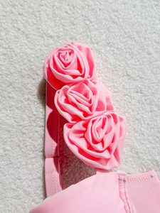Pink bikini top with 3D floral roses and underwire support on white fleece texture