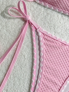 Pink textured bikini set with wavy scalloped edges and side tie detailing on white fur