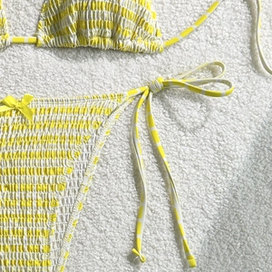 Détail d'un bikini smocké à rayures jaunes et blanches avec cordons latéraux et nœuds