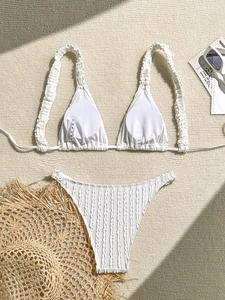 Detailed view of white textured bikini fabric with size S wash label on woven background