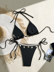 Detail of black ribbed bikini bottom with white crochet lace and seashell charm