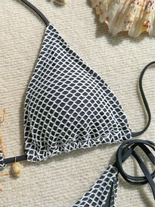 Detail of mesh bikini top with black lining, ties and decorative natural seashell charm