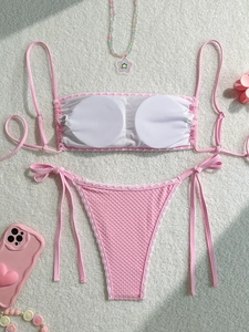 Pink textured bikini set with wavy trim and adjustable straps on white fuzzy background