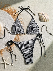 Detailed view of mesh bikini set with shell charms on a rustic textured background