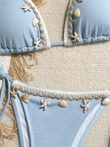 Detail of light blue ribbed bikini with white woven trim and seashell star pendants