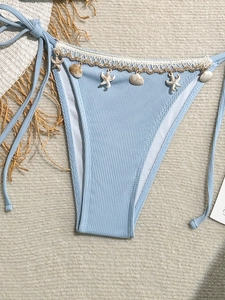 Detail of light blue ribbed bikini bottoms with seashell and starfish pendants on sand