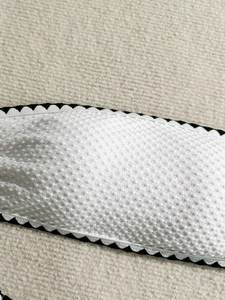 Close-up of white shell lace edge with embossed dot texture on a bikini swimwear fabric