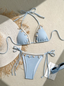 Close-up of light blue bikini with sea shells and starfish details on textured fabric