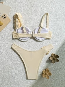 Detailed view of cream ruffled bikini top with underwire on soft white texture