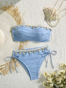 Vista piatta di un bikini azzurro con tessuto testurizzato e ciondoli di conchiglie