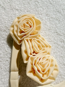 Detailed view of handmade cream fabric rose floral accents on the bikini shoulder strap